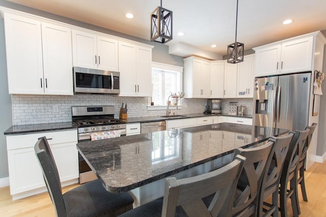 kitchen with light wood finished floors, appliances with stainless steel finishes, white cabinetry, and a sink