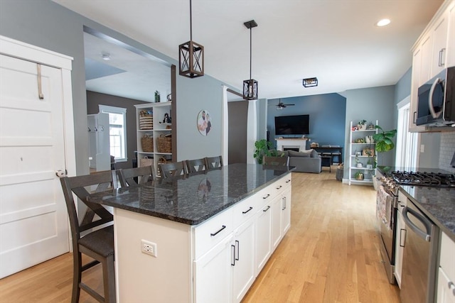 kitchen featuring stainless steel appliances, light wood-style floors, a breakfast bar area, and a fireplace