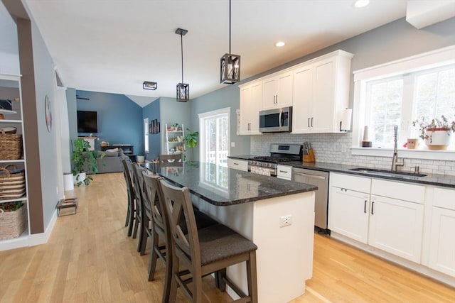 kitchen featuring tasteful backsplash, white cabinetry, stainless steel appliances, and a sink