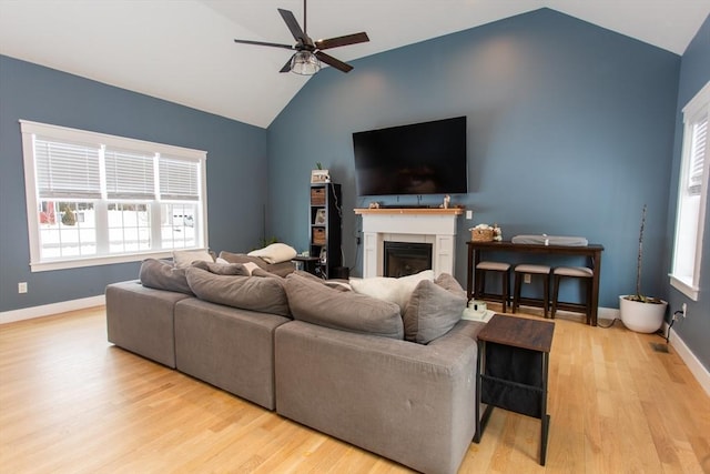 living room featuring baseboards, lofted ceiling, wood finished floors, and a fireplace