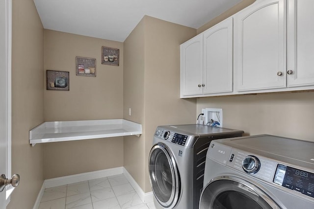 clothes washing area with cabinet space, baseboards, washing machine and dryer, and light marble finish flooring