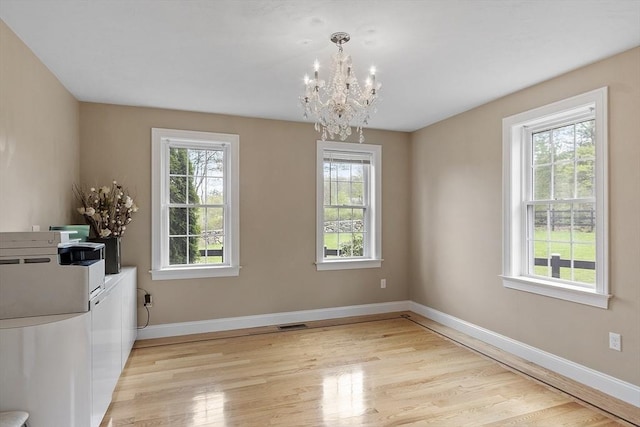 unfurnished dining area featuring a chandelier, light wood-style floors, and baseboards