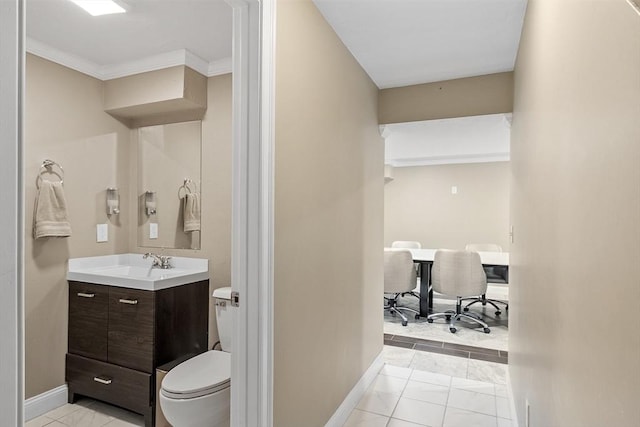 bathroom with toilet, baseboards, vanity, and crown molding