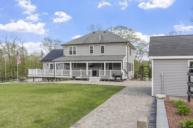 rear view of house with a lawn, solar panels, cooling unit, and a shingled roof