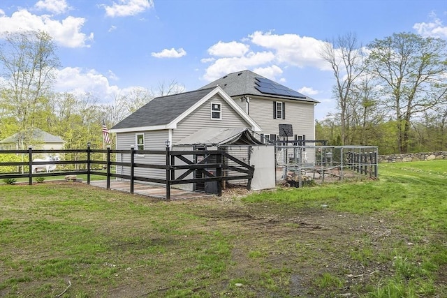 back of property with a shingled roof and roof mounted solar panels