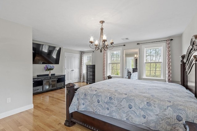 bedroom featuring a chandelier, light wood-type flooring, and baseboards