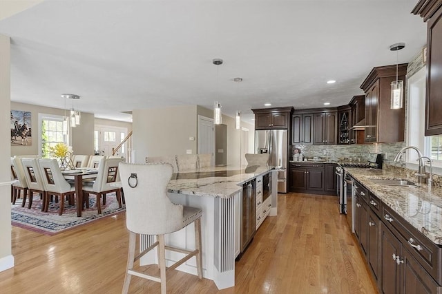 kitchen with stainless steel appliances, a sink, healthy amount of natural light, dark brown cabinetry, and recessed lighting