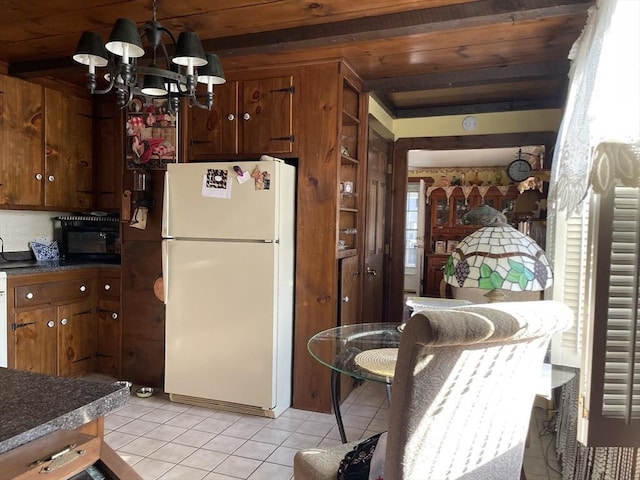 kitchen featuring dark countertops, wood ceiling, light tile patterned flooring, and freestanding refrigerator