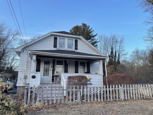 bungalow-style house with covered porch, roof with shingles, and a fenced front yard