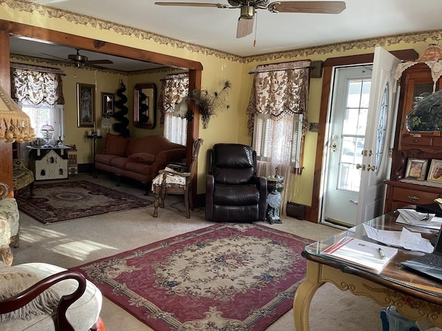 living room with light carpet, ceiling fan, baseboards, and a wealth of natural light