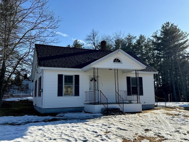 view of front of house featuring covered porch, a chimney, and a shingled roof