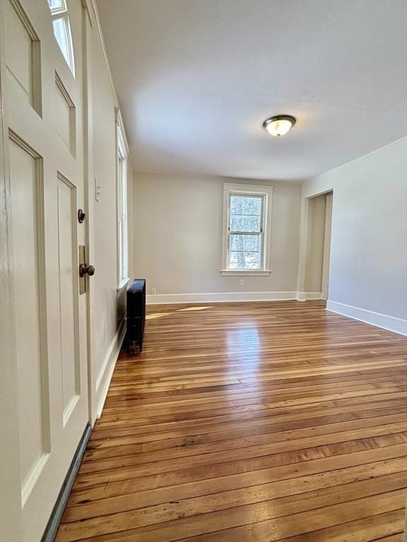 spare room with baseboards and wood finished floors