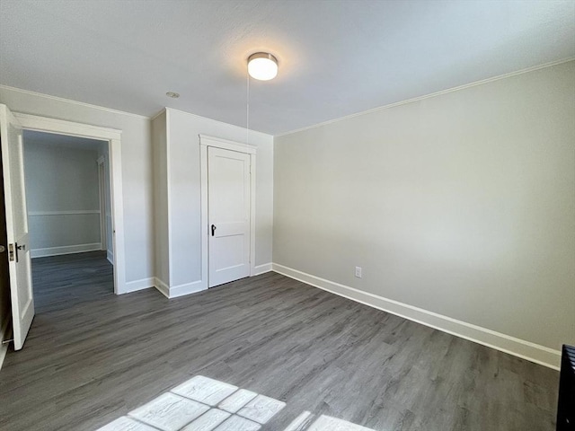 unfurnished bedroom featuring dark wood finished floors, baseboards, and ornamental molding