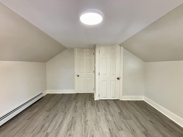 bonus room featuring a baseboard heating unit, baseboards, wood finished floors, and vaulted ceiling