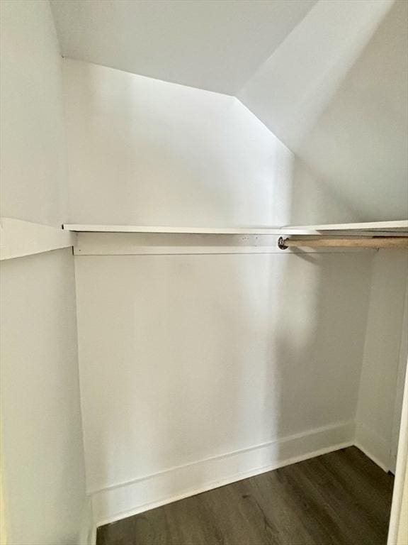 walk in closet featuring dark wood-type flooring and vaulted ceiling