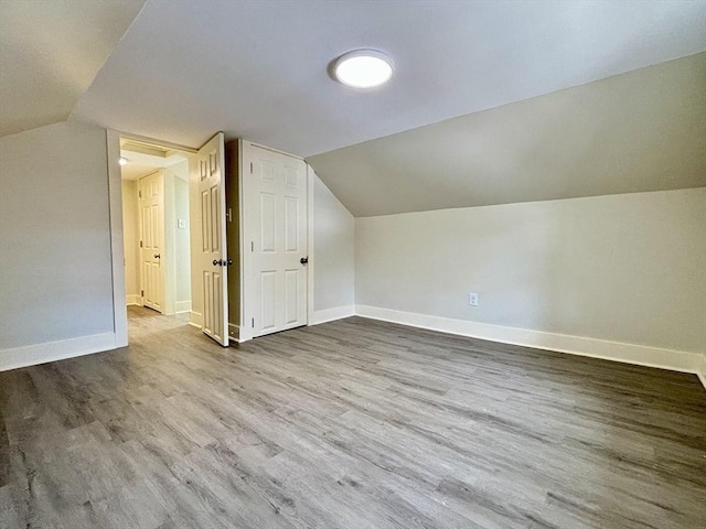 bonus room featuring baseboards, wood finished floors, and vaulted ceiling