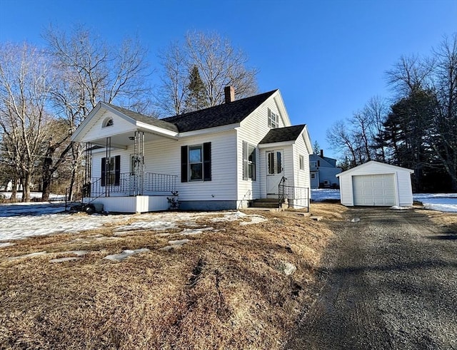 view of front facade featuring an outbuilding, driveway, a detached garage, a porch, and a chimney