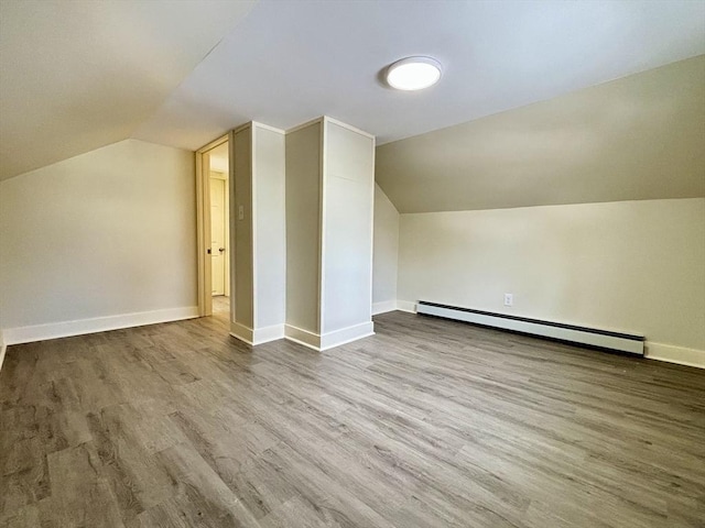 additional living space with lofted ceiling, wood finished floors, baseboards, and a baseboard radiator