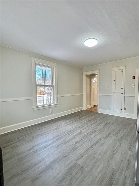 spare room featuring a textured ceiling, dark wood-type flooring, and baseboards