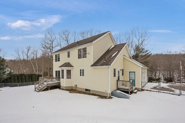 snow covered back of property with a wooden deck