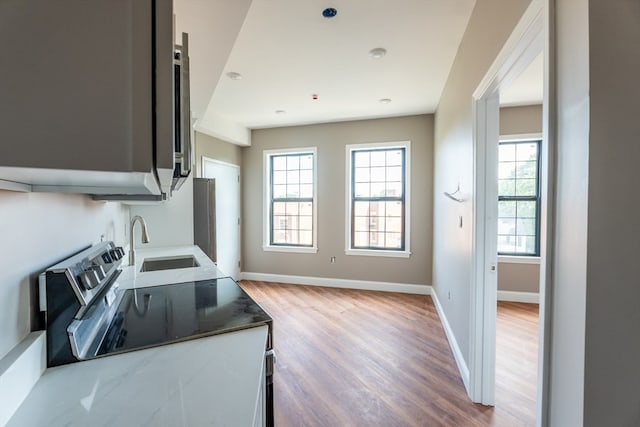 kitchen featuring light stone counters, sink, light wood-type flooring, and electric range