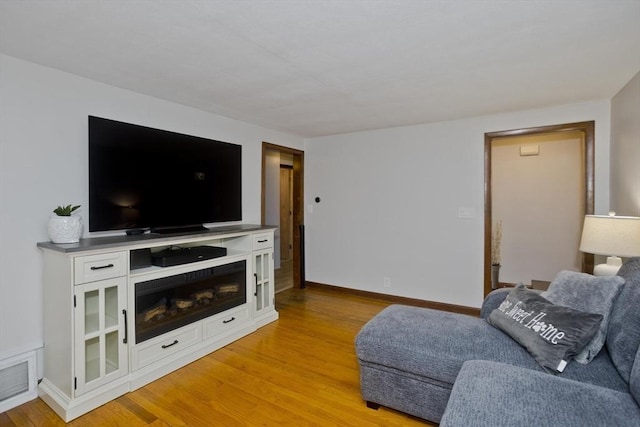 living room featuring baseboards, light wood-type flooring, and visible vents