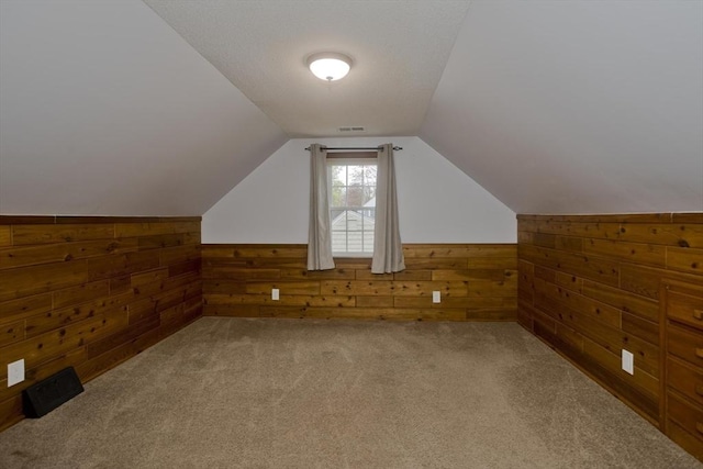bonus room featuring wooden walls, carpet, vaulted ceiling, and wainscoting