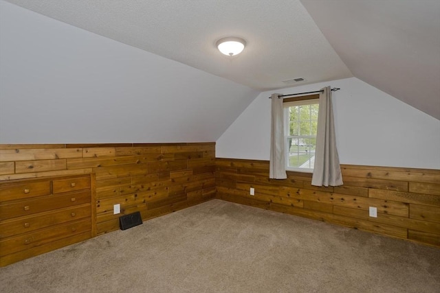 bonus room with carpet floors, vaulted ceiling, wood walls, and visible vents