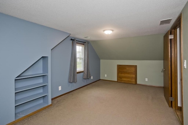 additional living space featuring visible vents, carpet flooring, a textured ceiling, and baseboards