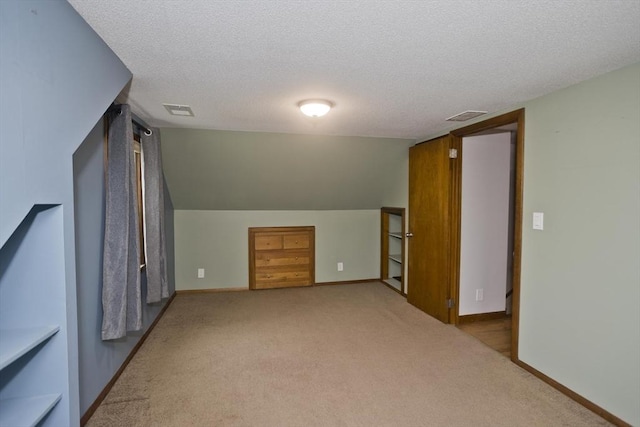 additional living space with a textured ceiling, light colored carpet, and visible vents