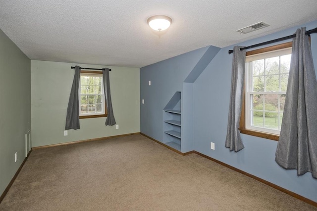 additional living space with visible vents, carpet flooring, a textured ceiling, and baseboards