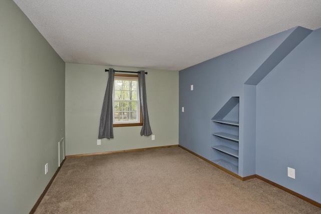 interior space with baseboards, carpet flooring, a textured ceiling, and built in features