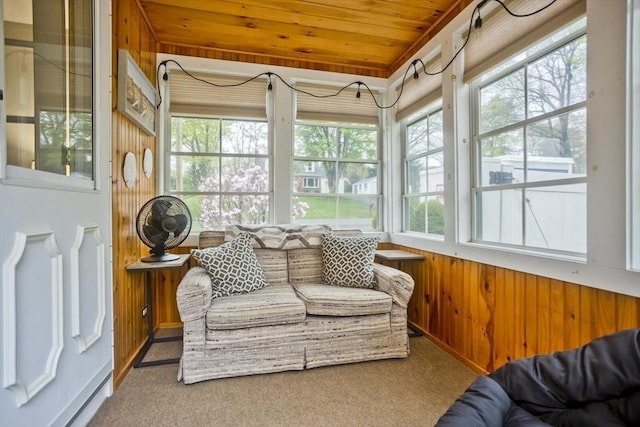 sunroom with a healthy amount of sunlight, wood ceiling, carpet flooring, and wood walls