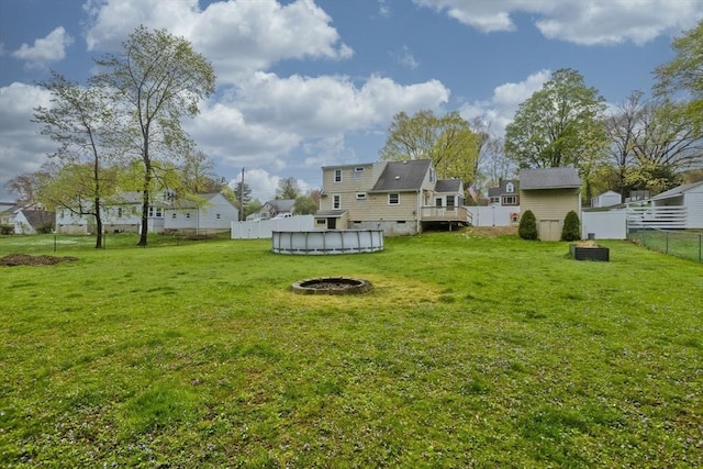 view of yard featuring a deck, a residential view, a fenced in pool, a fenced backyard, and an outdoor fire pit
