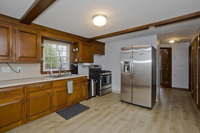 kitchen with brown cabinets, stainless steel appliances, beamed ceiling, and a sink