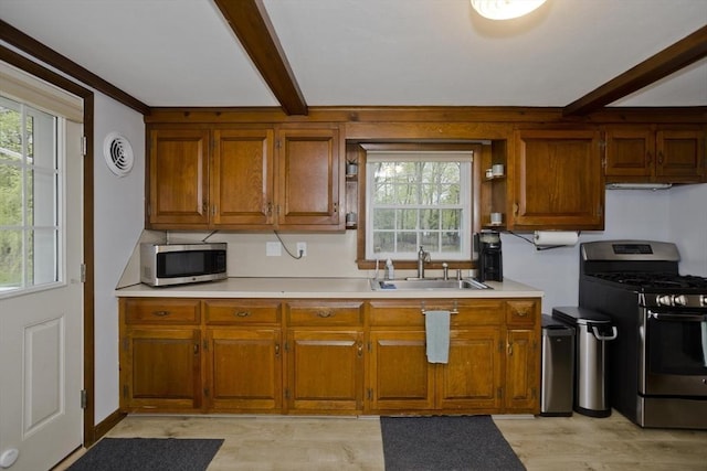 kitchen featuring light countertops, a sink, beam ceiling, and stainless steel appliances