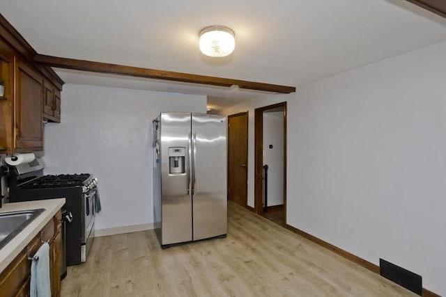 kitchen with light countertops, baseboards, stainless steel appliances, and light wood finished floors