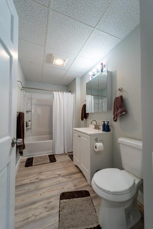 full bathroom with a paneled ceiling, vanity, toilet, hardwood / wood-style flooring, and shower / bath combo