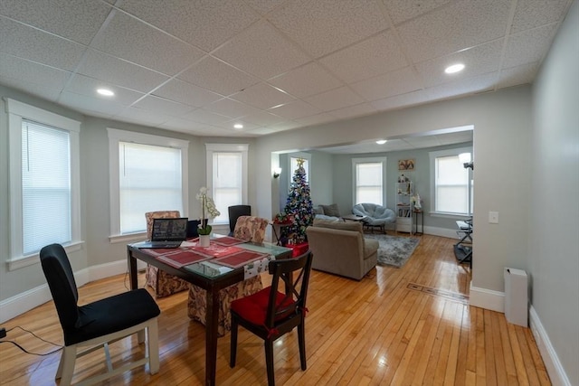 dining area featuring a drop ceiling, a wealth of natural light, and light hardwood / wood-style floors