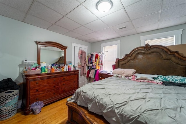 bedroom featuring a closet, wood-type flooring, and a drop ceiling