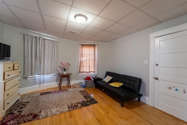 living area with a paneled ceiling and hardwood / wood-style floors