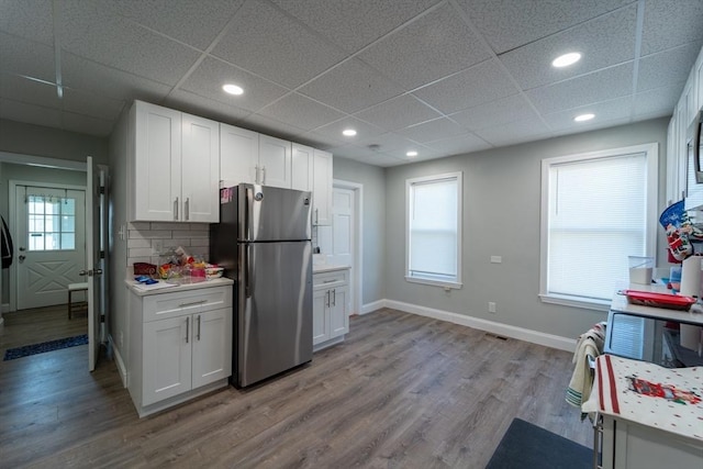 kitchen featuring white cabinets, a drop ceiling, and stainless steel refrigerator