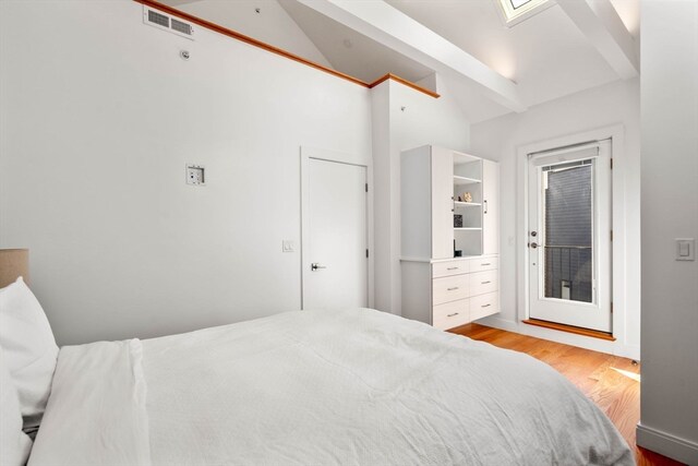 bedroom with lofted ceiling with skylight and light hardwood / wood-style floors