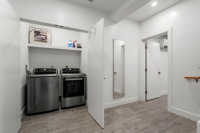 laundry area featuring washing machine and dryer, light wood-type flooring, and a wall mounted air conditioner