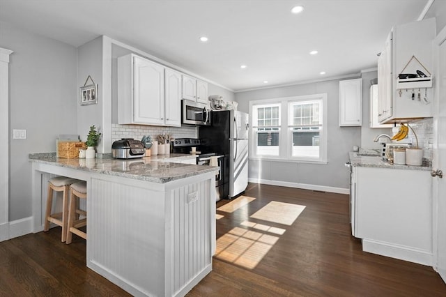 20-A Franklin St, Peabody, MA 01960 - kitchen featuring appliances with stainless steel finishes, decorative backsplash, light stone counters, a peninsula, and recessed lighting
