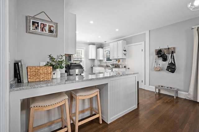 20-A Franklin St, Peabody, MA 01960 - kitchen with white cabinets, dark wood finished floors, a peninsula, light stone countertops, and a breakfast bar area