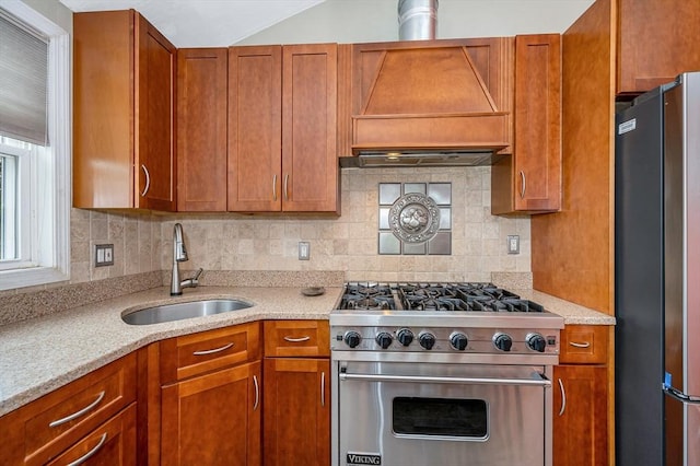 kitchen with appliances with stainless steel finishes, a sink, backsplash, and brown cabinetry