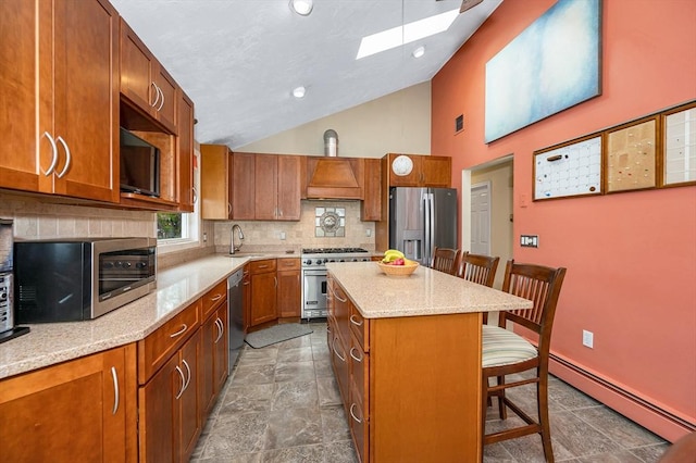kitchen with appliances with stainless steel finishes, baseboard heating, a sink, a kitchen bar, and a skylight