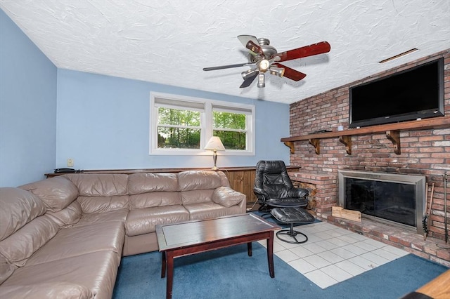 living area featuring ceiling fan, a brick fireplace, a textured ceiling, and carpet floors