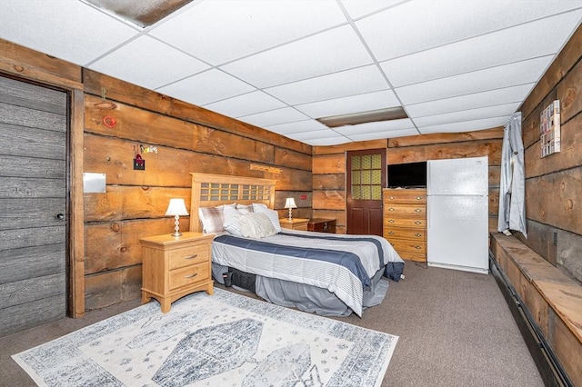 bedroom featuring carpet flooring, a drop ceiling, and wood walls